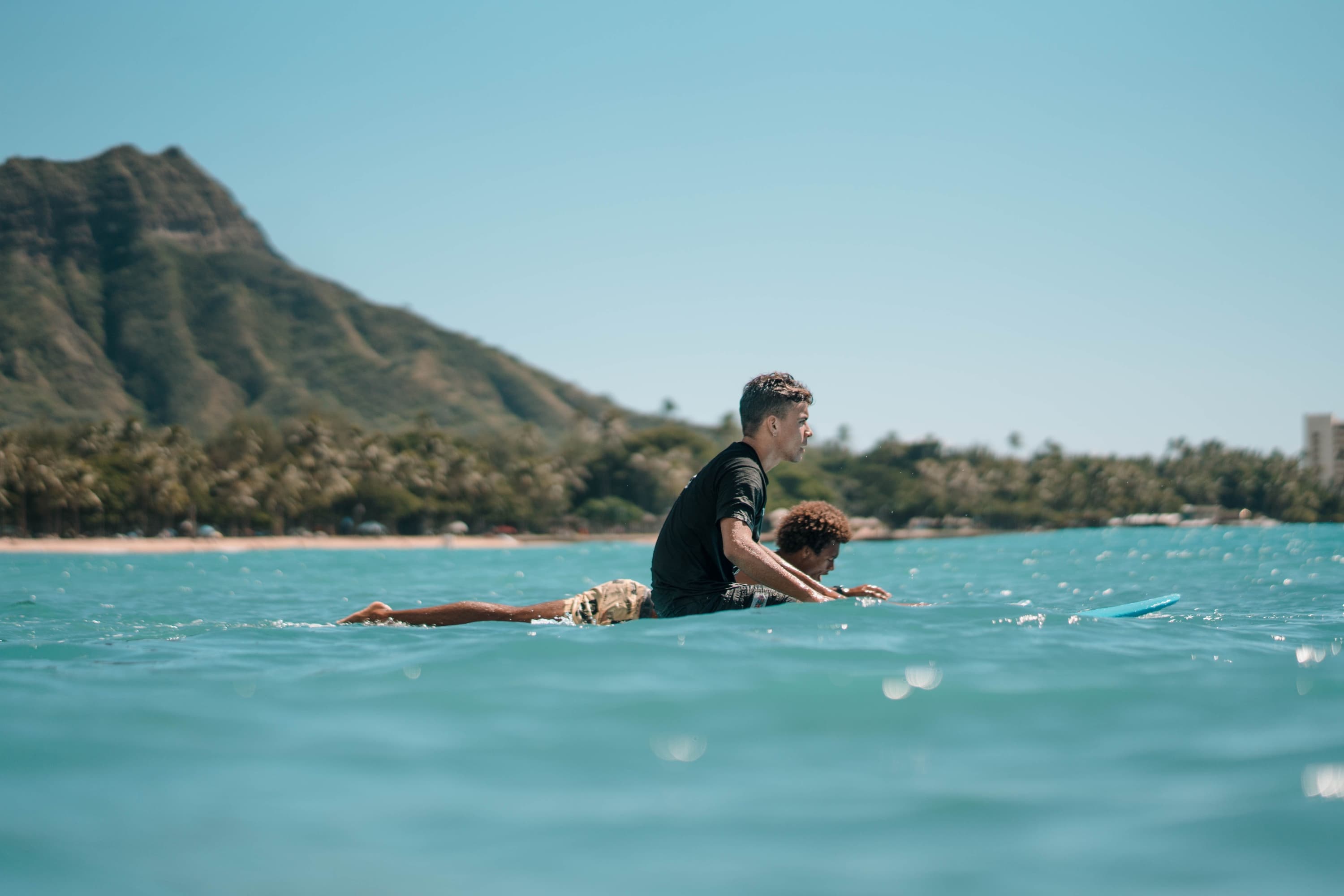 Two people resting on a surfboard near Diamond Head